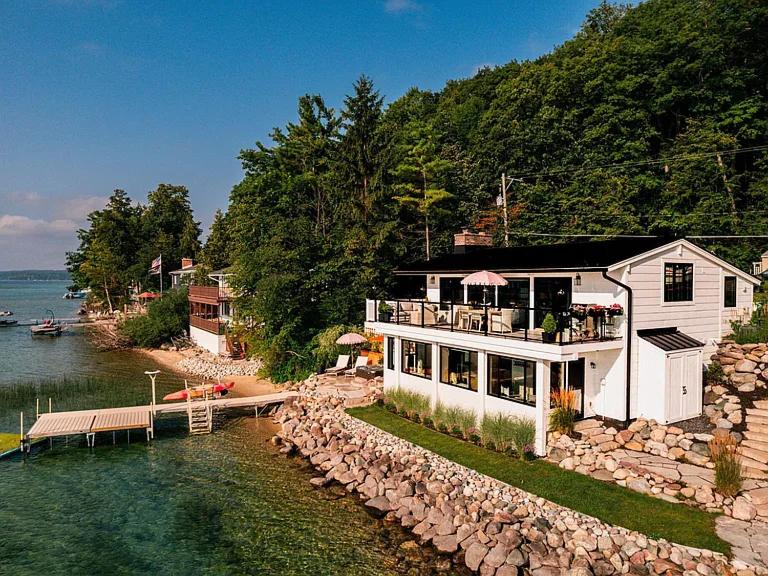 een groot huis aan de oever van een waterlichaam bij Water’s Edge Private Frontage + Dock Hot Tub AC in Traverse City