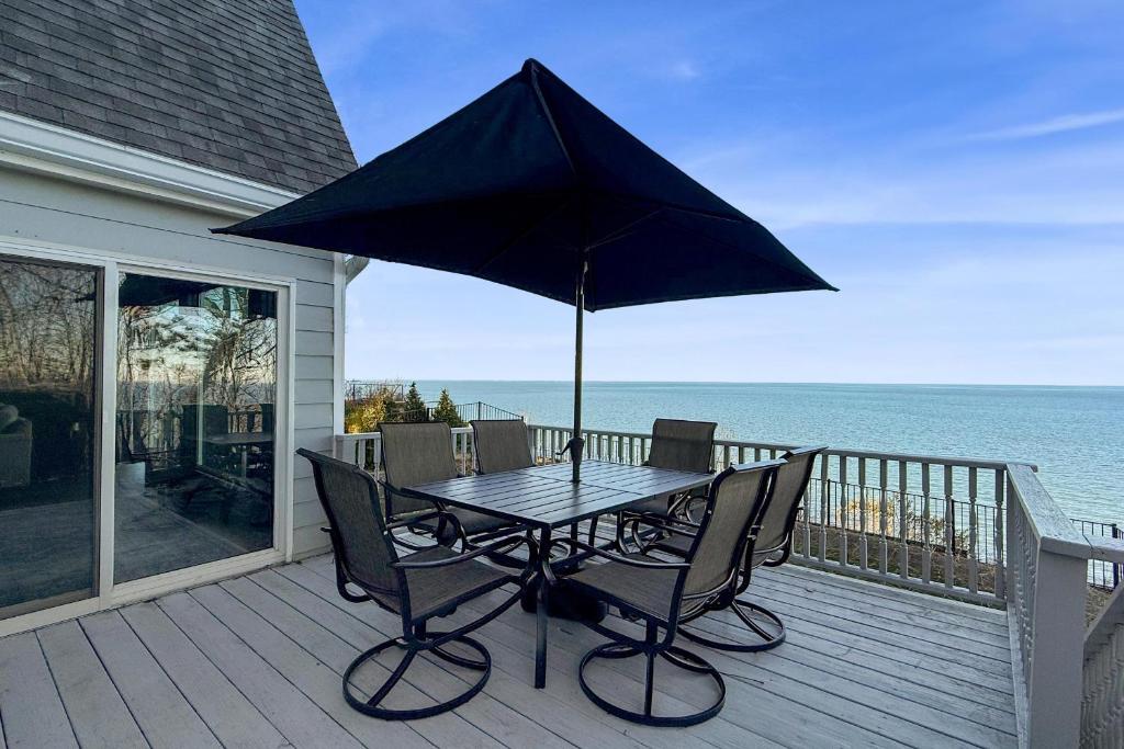 a table and chairs on a deck with an umbrella at Scenic Gem: Waterfront View, Beach Access in Wading River