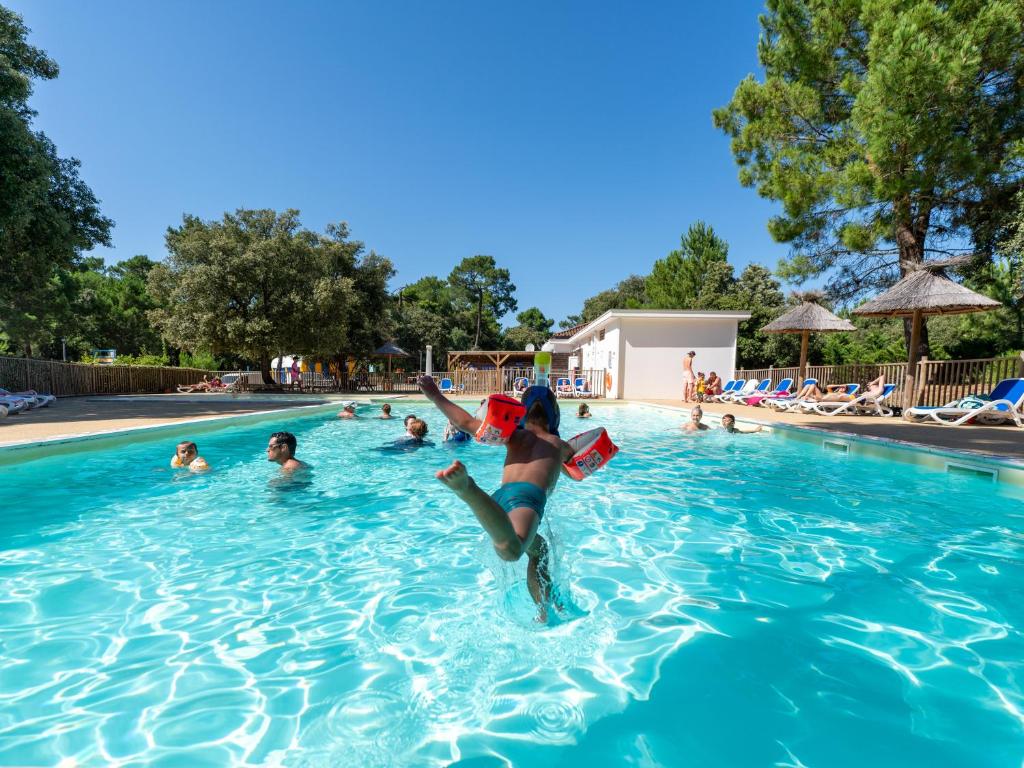 a young girl jumping into a swimming pool at Domaine Résidentiel de Plein Air Monplaisir in Saint-Trojan-les-Bains
