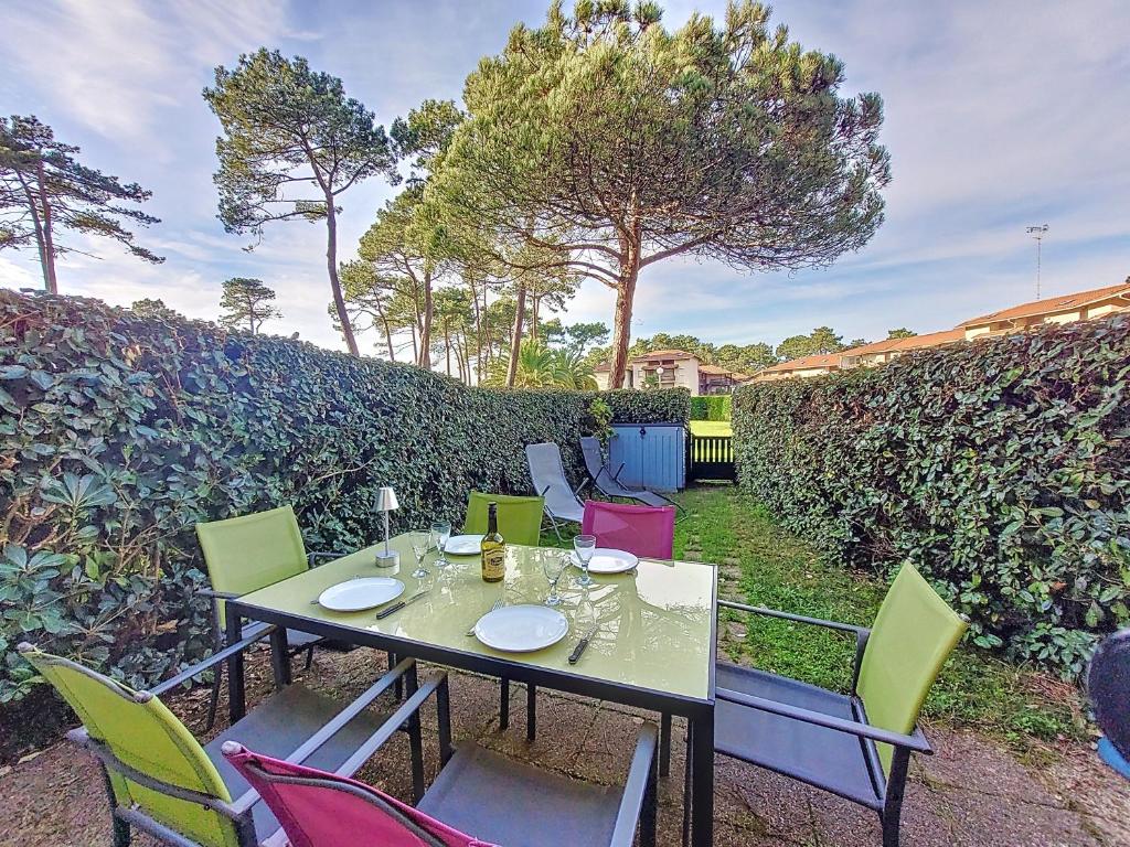 une table avec des chaises colorées assises sur une terrasse dans l'établissement S-Plage 02-Soustons Joli petit appartement avec jardin et piscine pour 4 personnes, à Vieux-Boucau-les-Bains