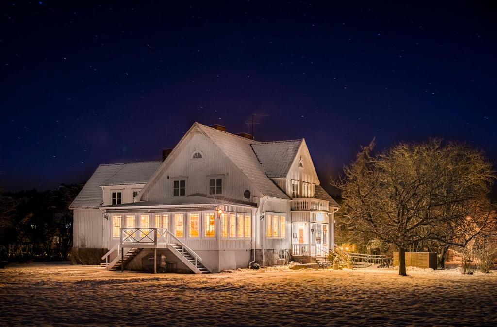 Une grande maison blanche avec des fenêtres éclairées la nuit dans l'établissement Villa Bro, à Brastad