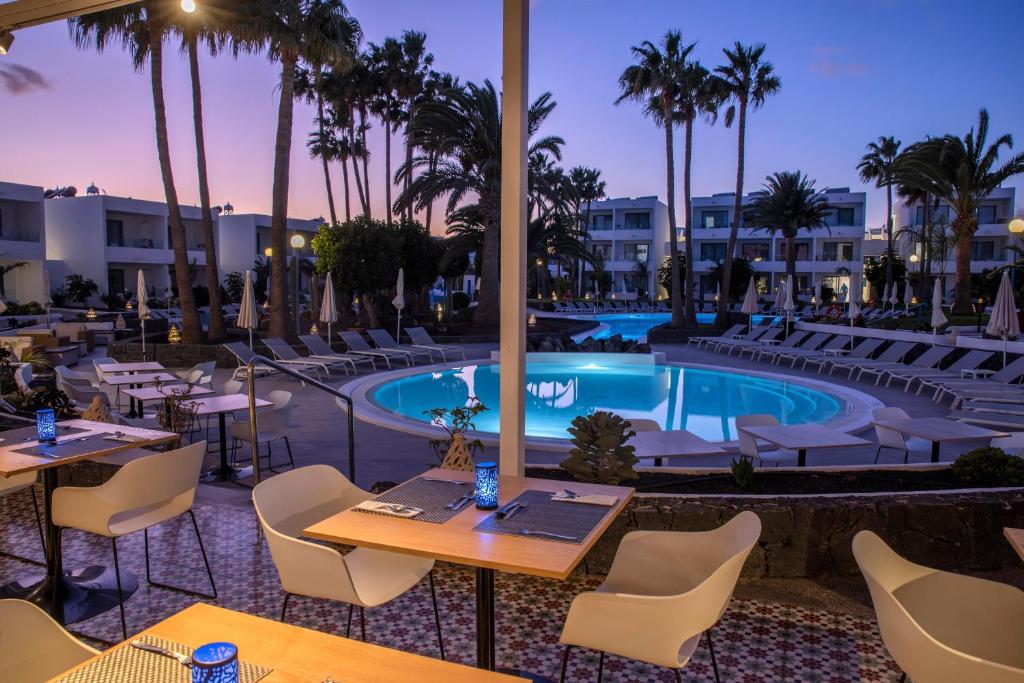 a hotel patio with tables and chairs and a swimming pool at Oasis Lanz Beach Mate in Costa Teguise