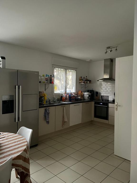 une cuisine avec des appareils en acier inoxydable et une table dans l'établissement Loue Maison événement circuit 24 heures Le Mans, à La Suze-sur-Sarthe