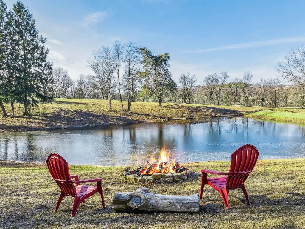 two chairs and a fire pit in front of a pond at Cottage Inn The Woods -- Pond, Pet Friendly, Grill, Wifi, Fire Pit, Deck, Screen Porch, Fireplace, Private in Berkeley Springs