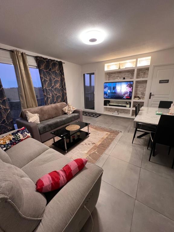 un salon avec deux canapés et une télévision dans l'établissement Apparemment près de CDG Paris & Disneyland, à Tremblay-en-France