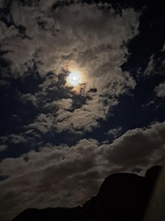 a cloudy sky with the moon in the sky at واي رم in Wadi Rum