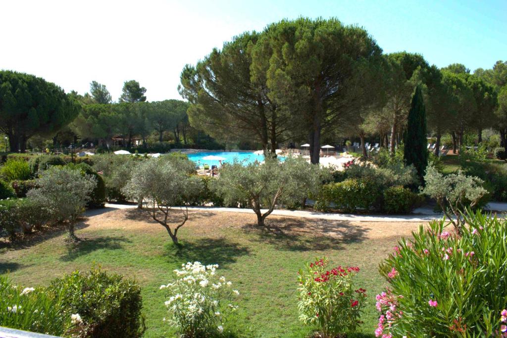 un jardin avec des arbres et une piscine en arrière-plan dans l'établissement Golf Fontaine, à Pont-Royal