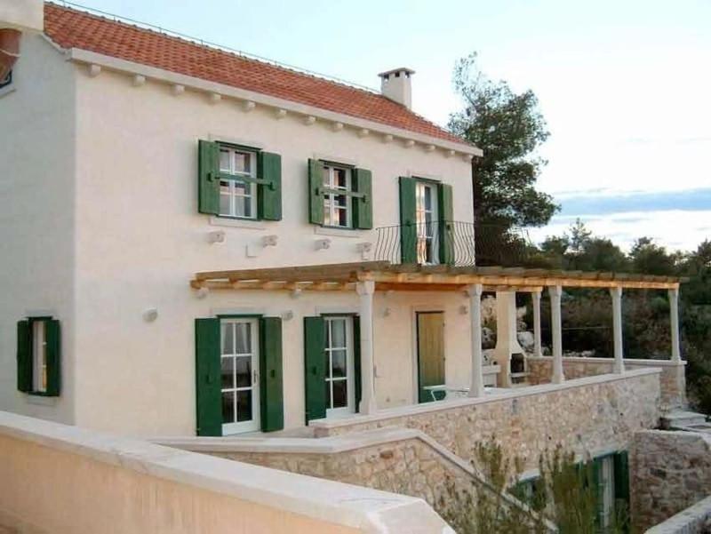 een wit huis met groene luiken en een veranda bij Villa Convalaria in Sutivan