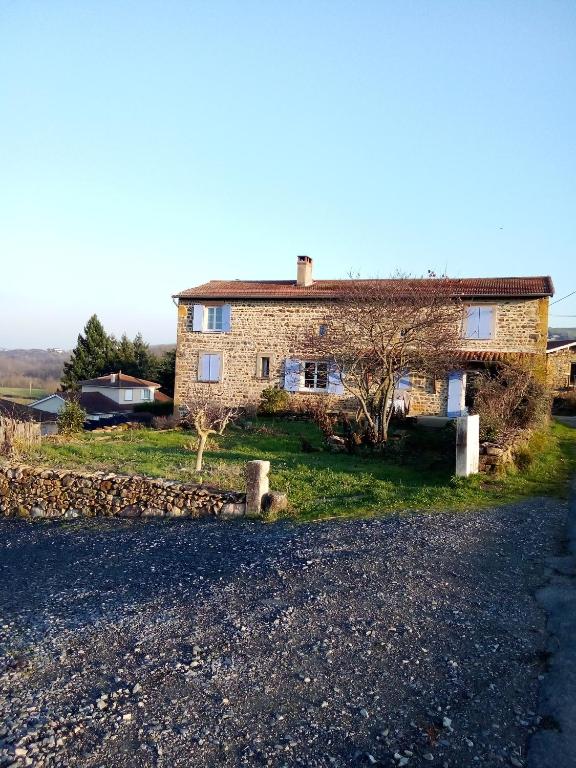 une grande maison en briques avec une route en gravier en face dans l'établissement Chez Steph, à Saint-Germain-Nuelles