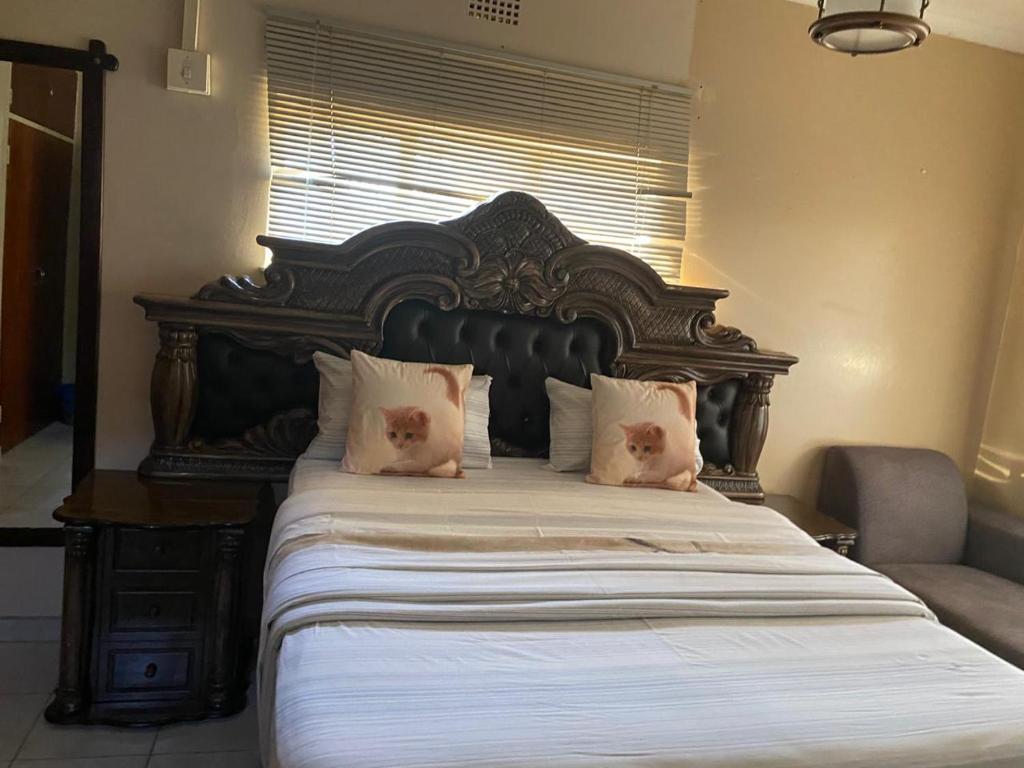 a large bed with a large wooden headboard and pillows at Savannah Guest House Mafikeng in Mahikeng