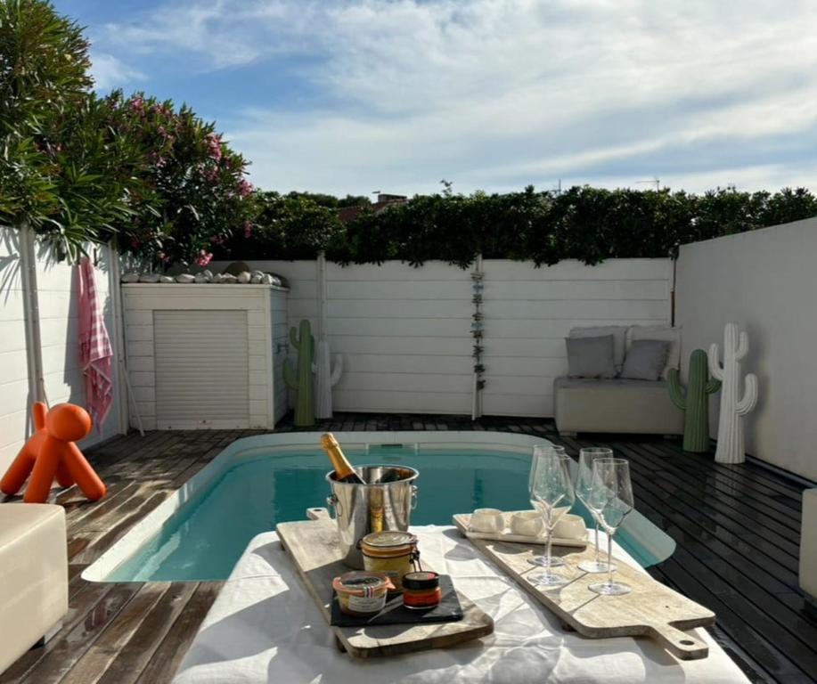 un patio avec une table et une piscine dans l'établissement La maison de la plage, à Canet