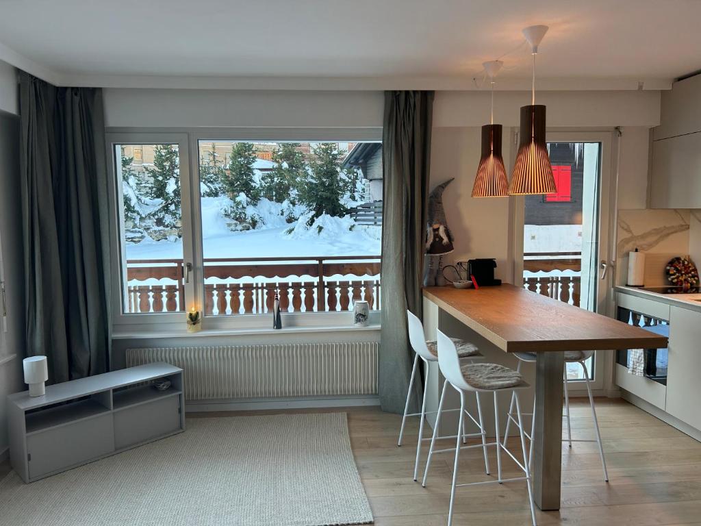 a kitchen with a table and a window with snow at New studio in Crans center in Crans-Montana