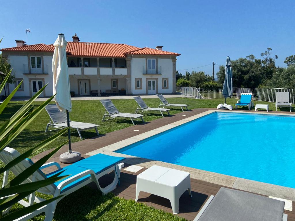 a swimming pool with chairs and a house in the background at Casa da Gândara in Ponte de Lima