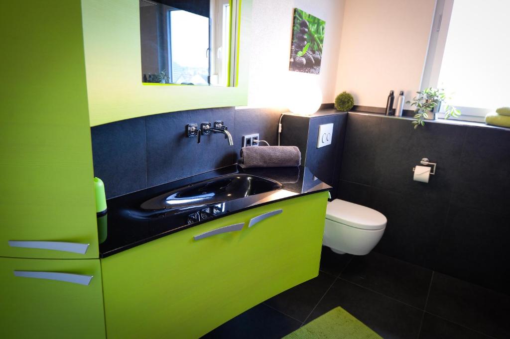 a green bathroom with a sink and a toilet at Ferienwohnung in Elz bei Limburg an der Lahn in Limburg an der Lahn
