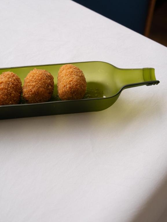 a green plate with four meatballs on a table at Hostal Empúries in L'Escala