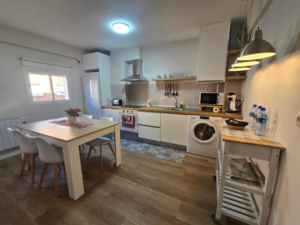 a kitchen with a table and a table and a kitchen with a washing machine at Martita Home in Zaragoza