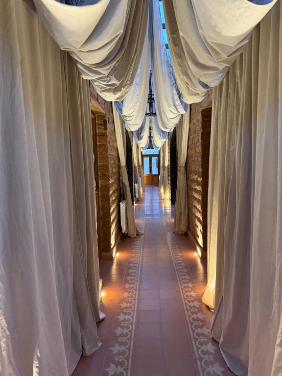 einen leeren Flur mit weißen Vorhängen und einem Flur in der Unterkunft Mitu in Purmamarca