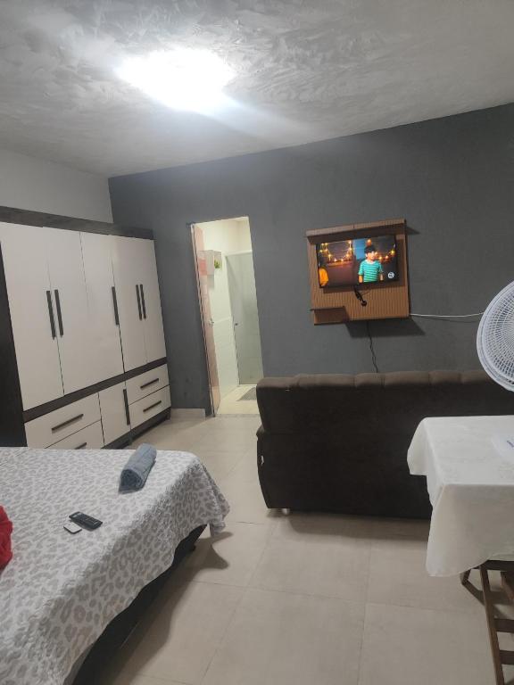 a bedroom with a couch and a tv on the wall at Studio mobiliado 3 in Contagem
