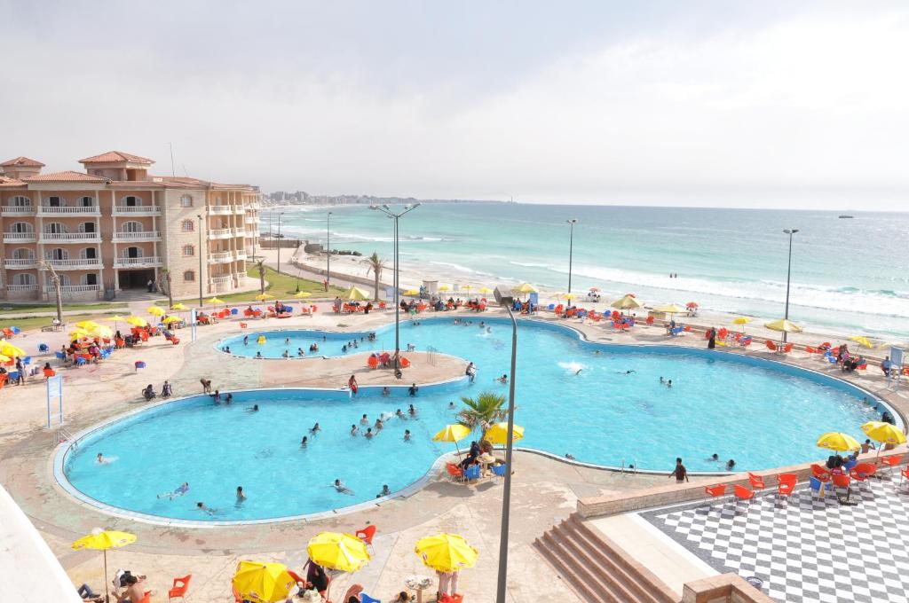 a group of people in a swimming pool next to the beach at Ajami Hotel Armed Forces Apartments in Alexandria