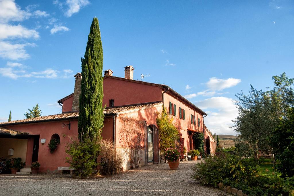 un viejo edificio rojo con un árbol delante de él en Villa Unica Sant'Alberto, en Campiglia dʼOrcia