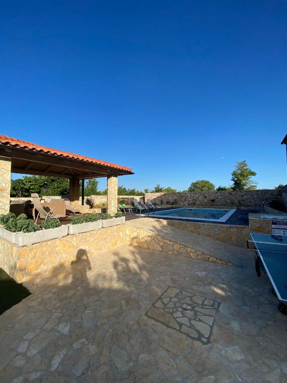 a stone patio with a pool and a pavilion at Apartments Dujo in Rupe