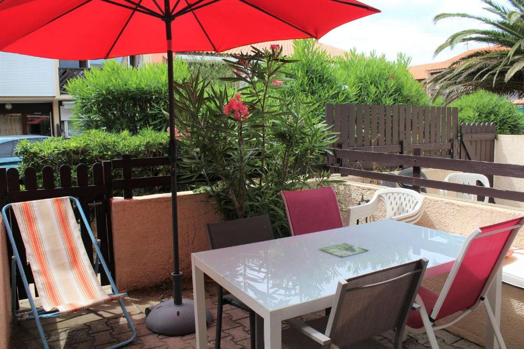 - une table et des chaises avec un parasol rouge sur la terrasse dans l'établissement APPARTEMENT 3 pieces PORT LA NOUVELLE PN340-126, à Port-la-Nouvelle