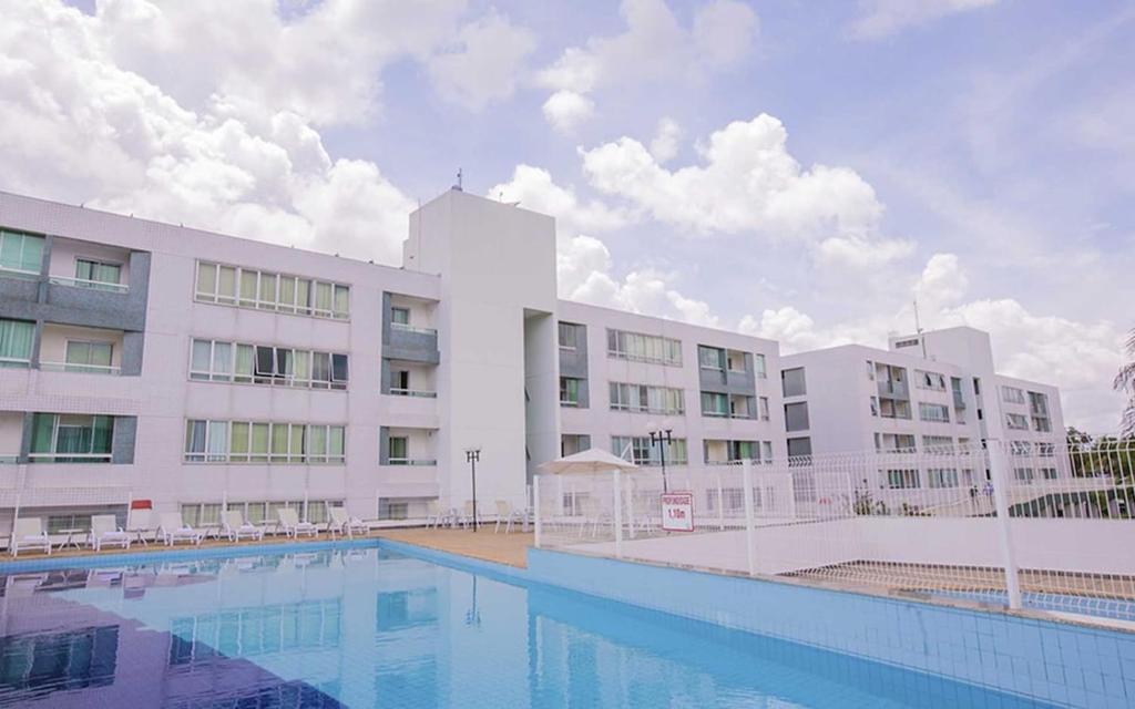 a large white building with a swimming pool in front of it at Premier Residence Hotel em Brasília 21604 in Brasilia