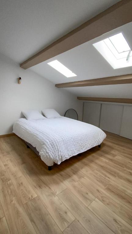 une chambre avec un lit blanc et un parquet dans l'établissement Appartement T2, à Béziers