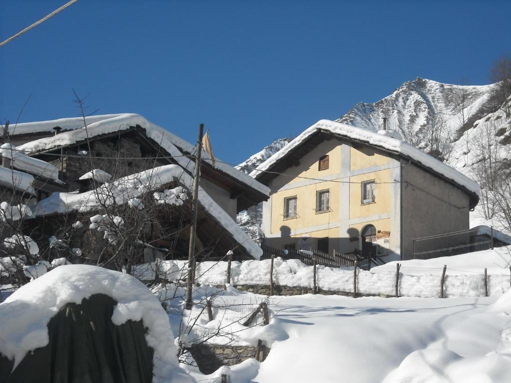 une maison recouverte de neige devant une montagne dans l'établissement B&B La Miando, à Salza di Pinerolo