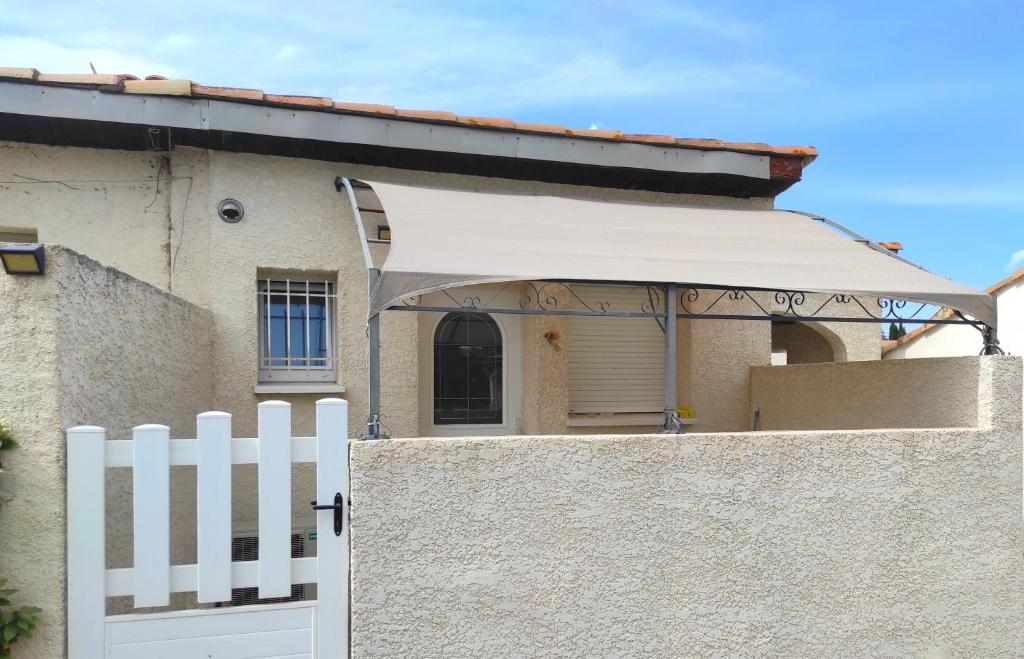 une clôture blanche devant une maison avec un auvent blanc dans l'établissement Les Lavandes du Moulin, à Puissalicon