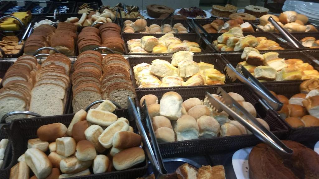 uma exposição de diferentes tipos de pão e pastelaria em Hotel Santos Reis em Aparecida