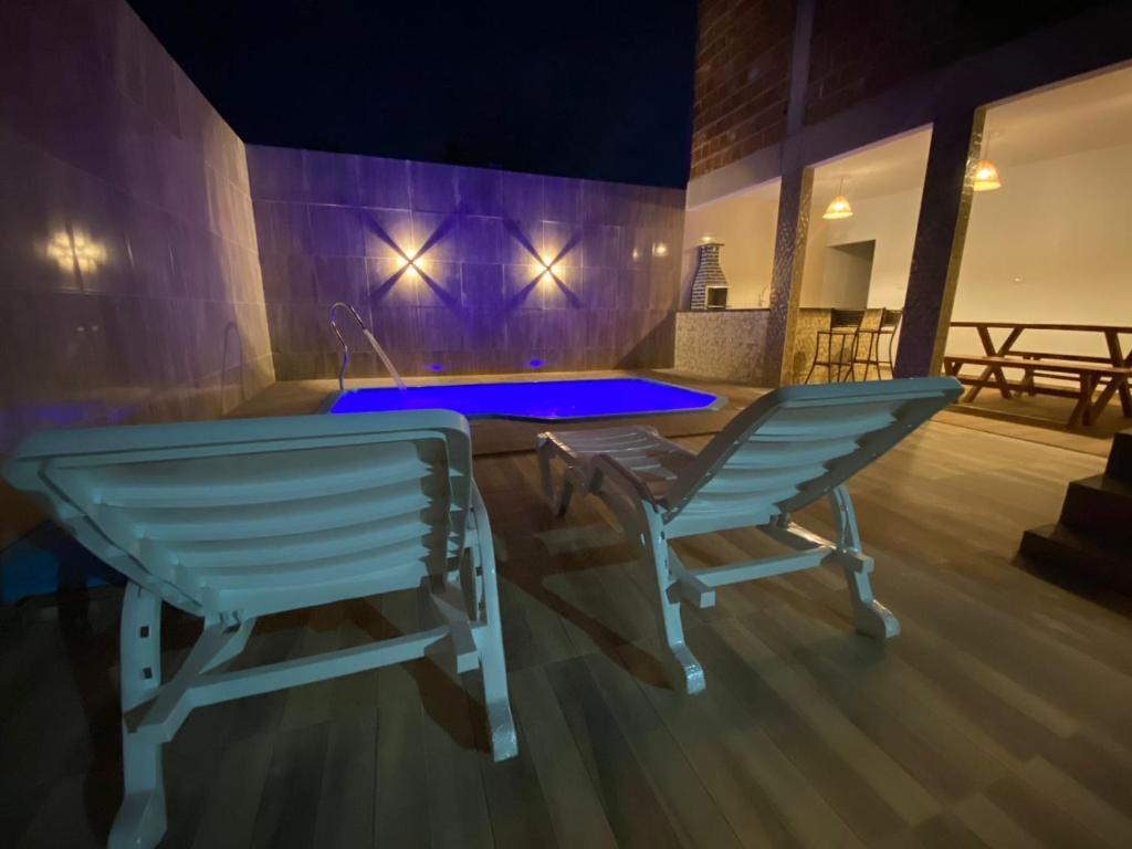 サン・ミゲル・ドス・ミラーグレスにあるRecanto Dourado Qt Individualの椅子2脚とテーブル1台、プールが備わる客室です。