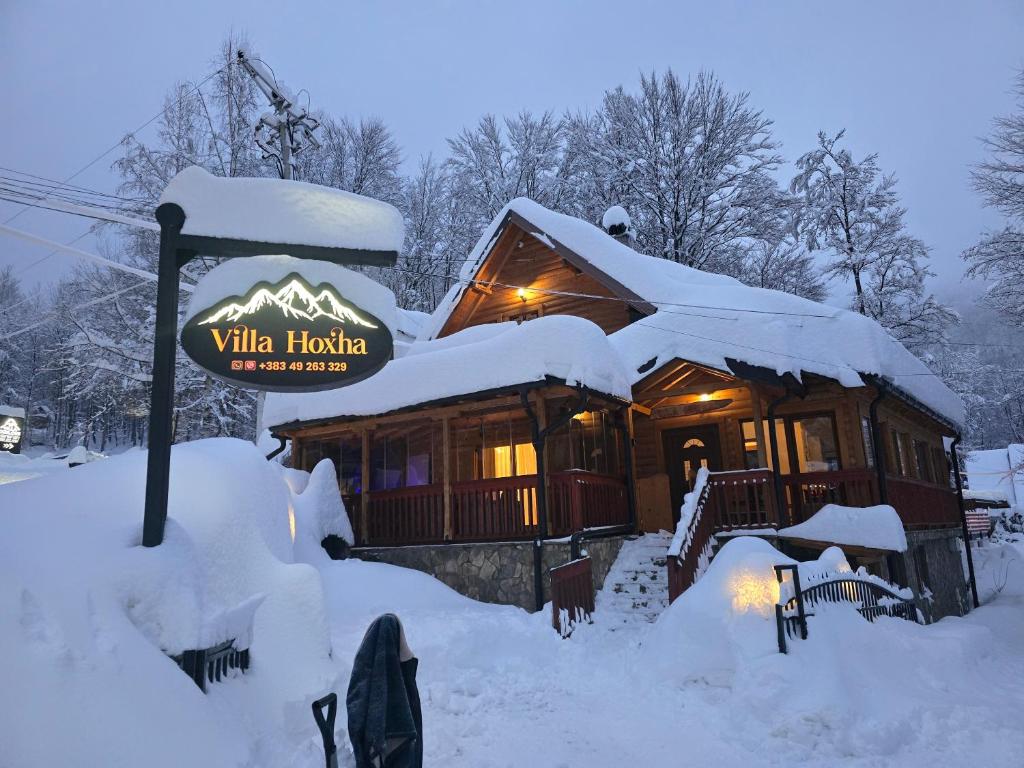 a log cabin in the snow with a sign at Villa Hoxha Brezovicë in Brezovicë
