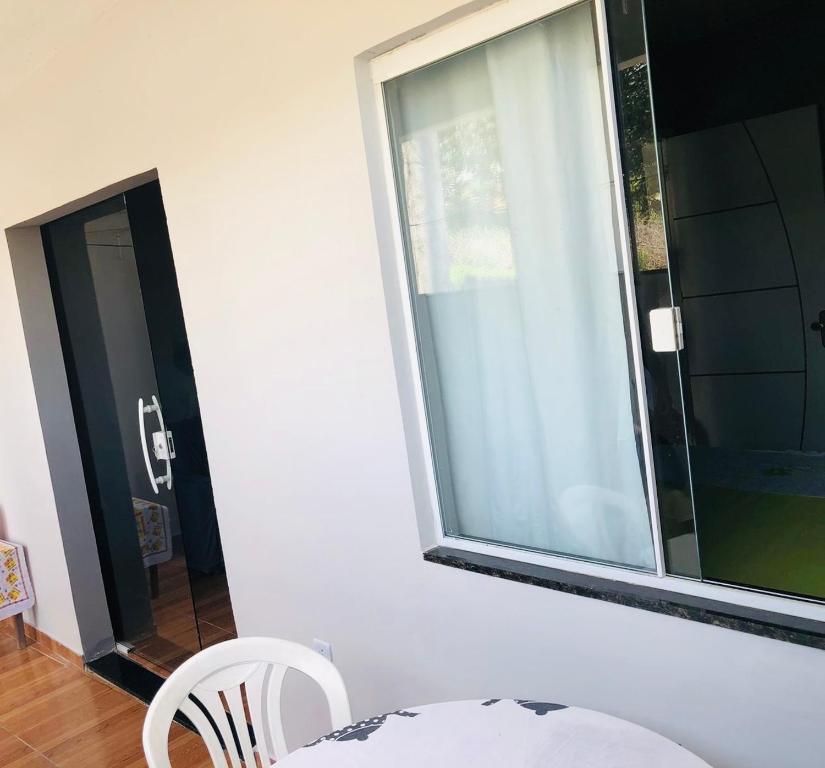 une chambre avec une fenêtre et deux chaises blanches dans l'établissement Cantinho Oliveiras, à Cabo Frio