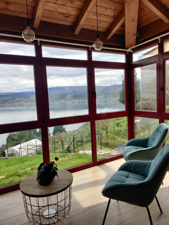 a living room with a table and chairs and windows at Casa da Ramona in Ribadavia