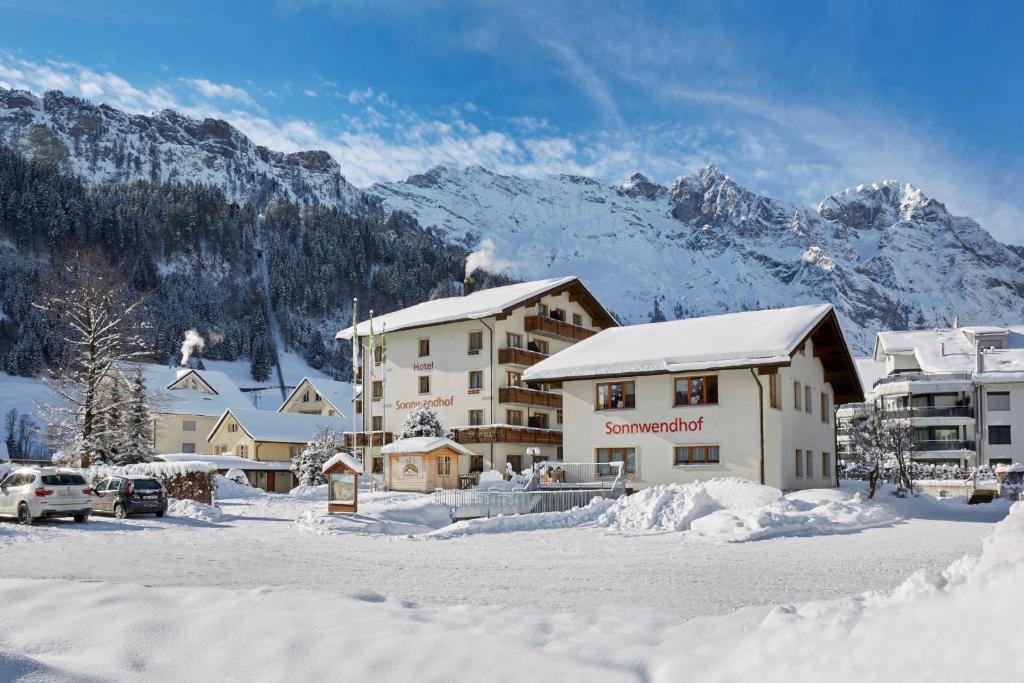 a hotel in the snow with mountains in the background at Hotel Sonnwendhof Engelberg in Engelberg