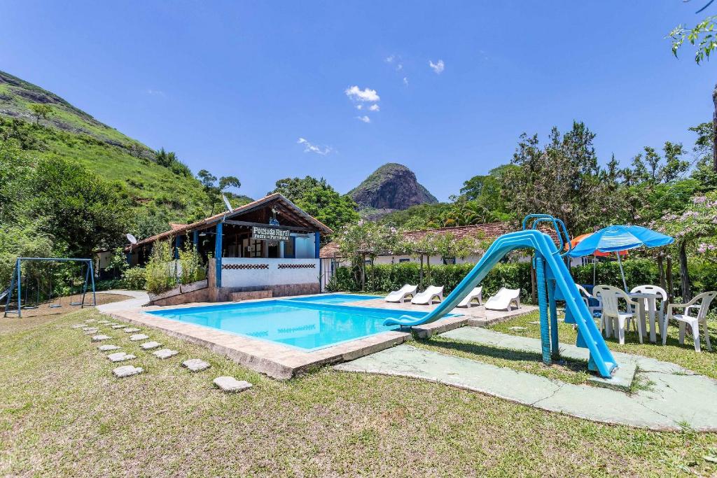 a pool with a slide in a yard with a house at Pousada Pedra de Paraibuna in Comendador Levy Gasparian