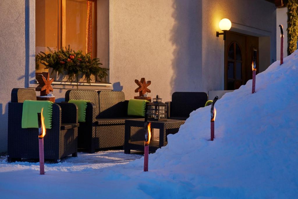 a snow covered porch of a house with chairs and tables at Hotel Sonnwendhof Engelberg in Engelberg