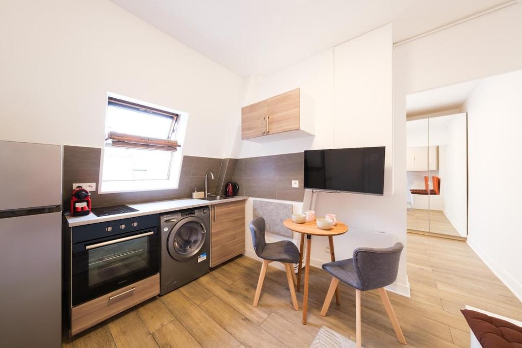 Il comprend une cuisine équipée d'une table, de chaises et d'un lave-vaisselle. dans l'établissement Beautiful Studio Trudaine-Marguerite, à Paris