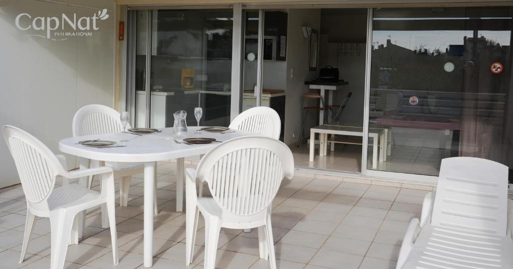 une table blanche et des chaises sur une terrasse dans l'établissement CapNat - Village Naturiste - Port Nature - Villa Pamela, au Cap d'Agde