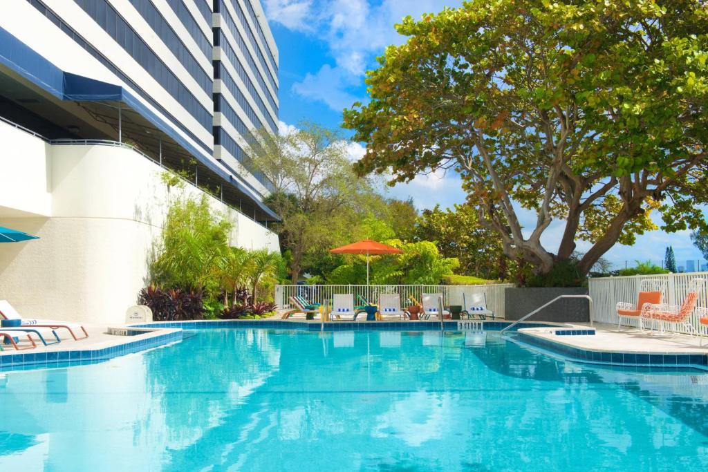 a swimming pool with chairs and umbrellas next to a building at Sheraton Miami Airport Hotel and Executive Meeting Center in Miami