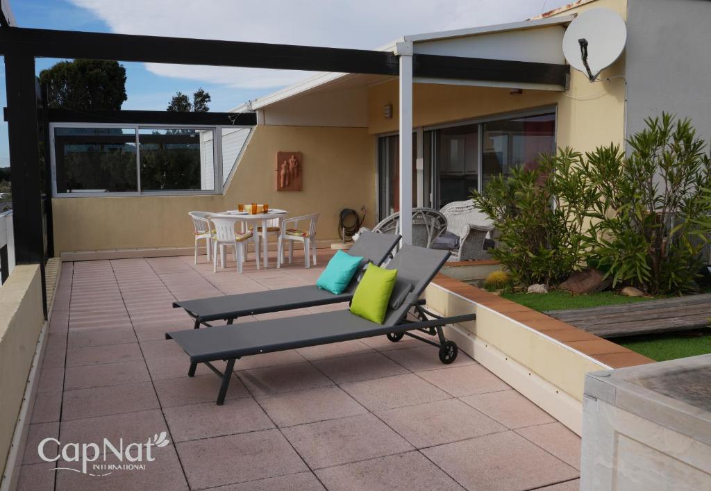 un patio avec deux chaises et un parasol dans l'établissement CapNat - Village Naturiste - Port Nature - Villa Malibu, au Cap d'Agde