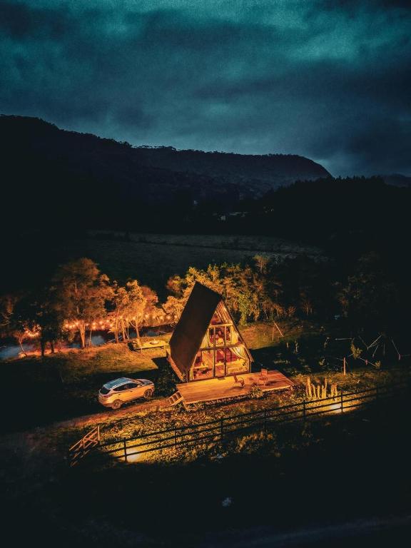 a small house with a car parked in a field at Cabana Uruma in Urubici