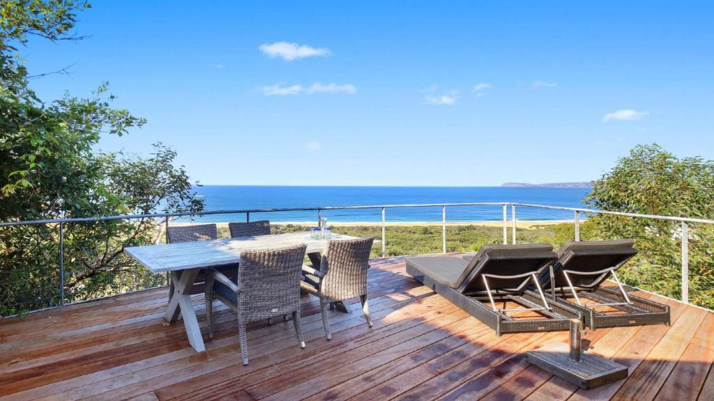 a deck with a table and chairs and the ocean at 'The Yurt' by HolidayCo in Hardys Bay