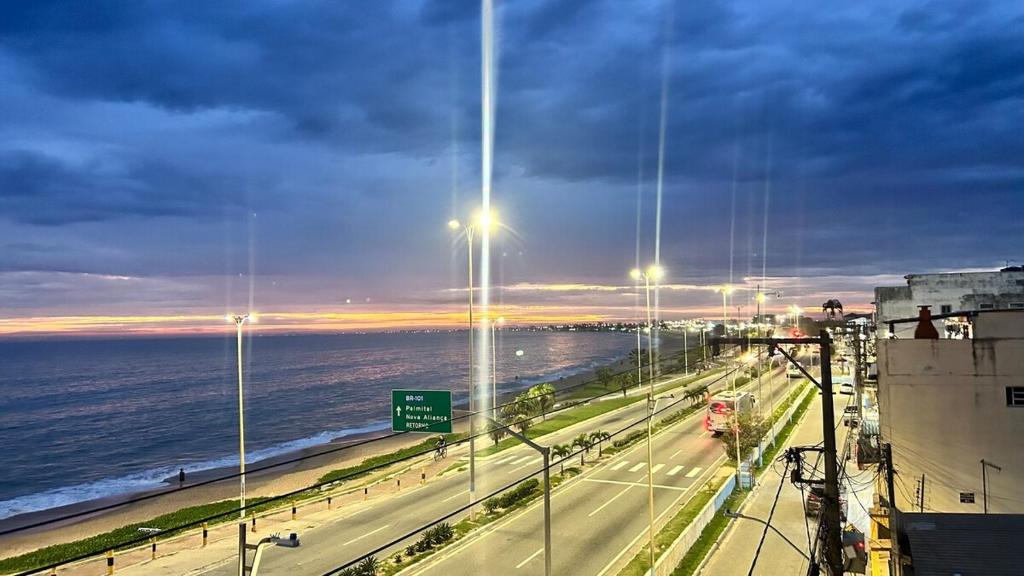 vistas a una autopista con el océano y las luces de la calle en AP Varanda do Mar - Rio das Ostras, en Rio das Ostras