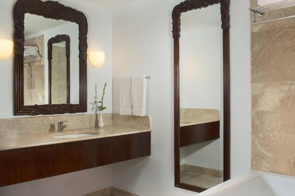 a bathroom with a sink and two mirrors at Sheraton Senggigi Beach Resort in Senggigi