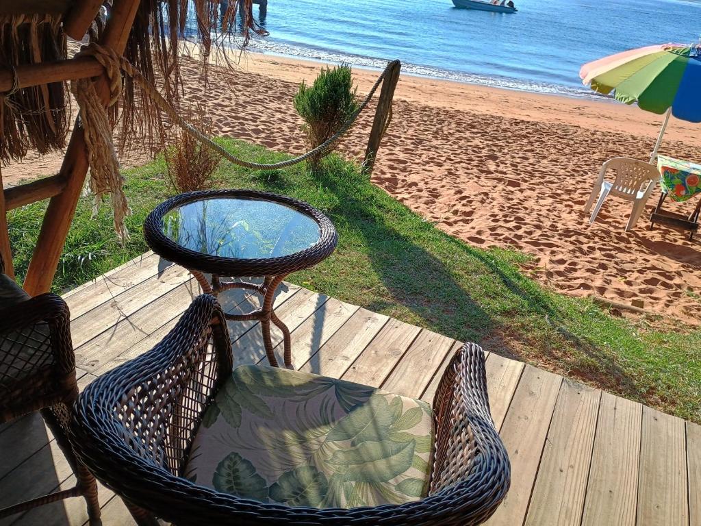 a hammock chair sitting on a deck next to the beach at Chalés do Pedro Hospedagem e Restaurante in Praia de Araçatiba