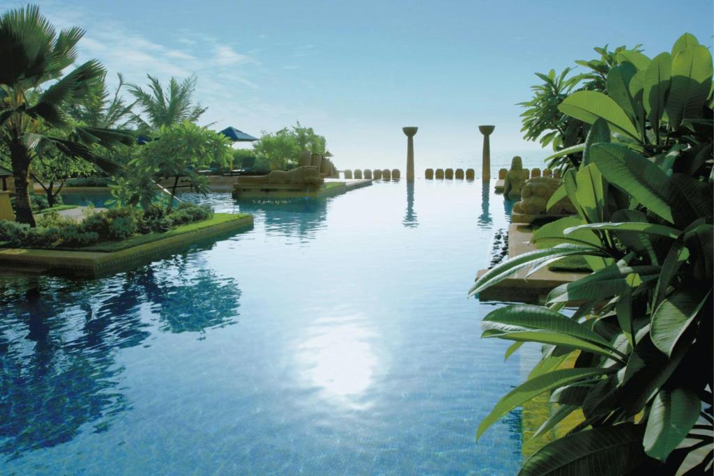 a pool at a resort with blue water and palm trees at JW Marriott Mumbai Juhu in Mumbai