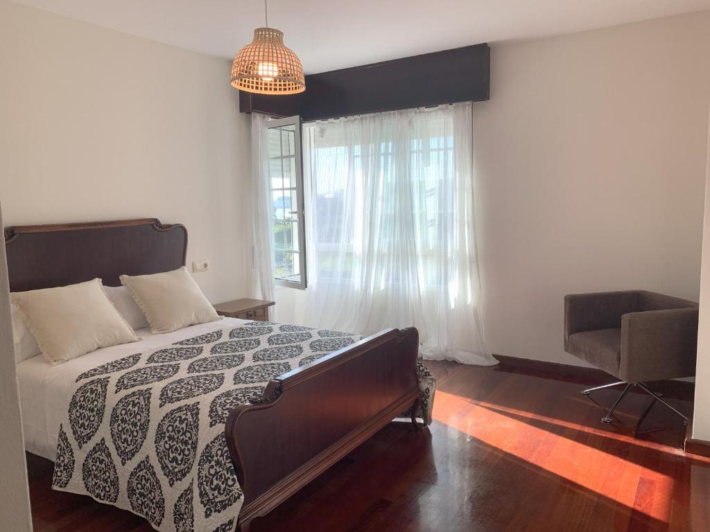 ein Schlafzimmer mit einem Bett und einem Stuhl und einem Fenster in der Unterkunft Casa das Cunchas a 50 metros de Area da Cruz in San Vicente do Mar