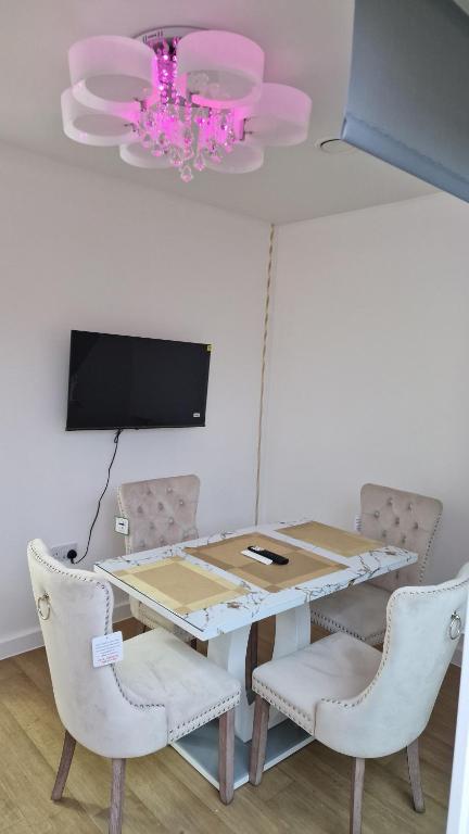 a dining room with a table and chairs and a tv at Romford Luxe Home in Goodmayes